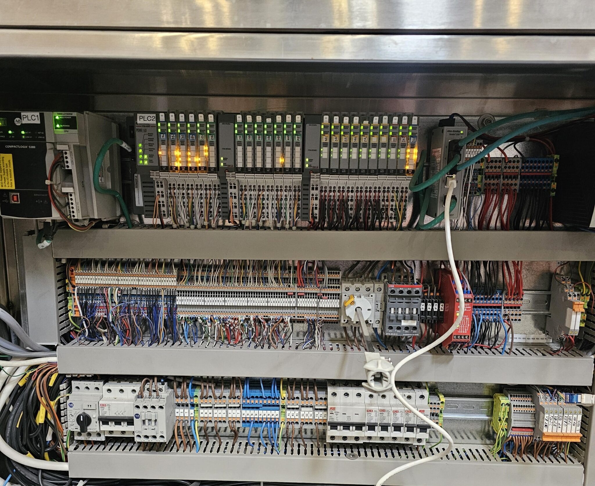 Motor control center backplate wired with breakers, PLC, and labeled terminal strips
